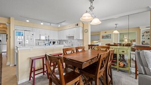 Uma cozinha moderna com armários brancos, uma mesa de jantar de madeira e iluminação pendente.