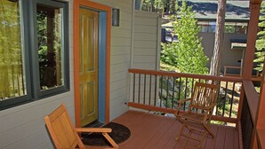 Une terrasse en bois avec deux chaises et une porte aux moulures colorées.
