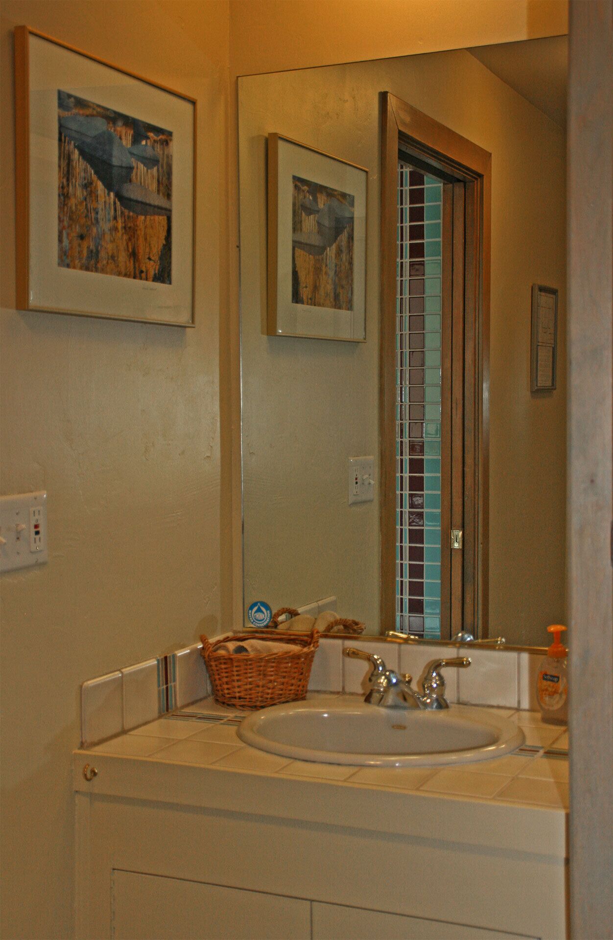 Ein Badezimmer mit Waschbecken, Spiegel und zwei gerahmten Kunstwerken an der Wand.