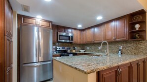 A kitchen with wooden cabinets, stainless steel appliances, granite countertops, and a built-in sink. - Come to your HAPPY PLACE! 2/2 ground floor waterfront community Condo! (Madeira Beach)
