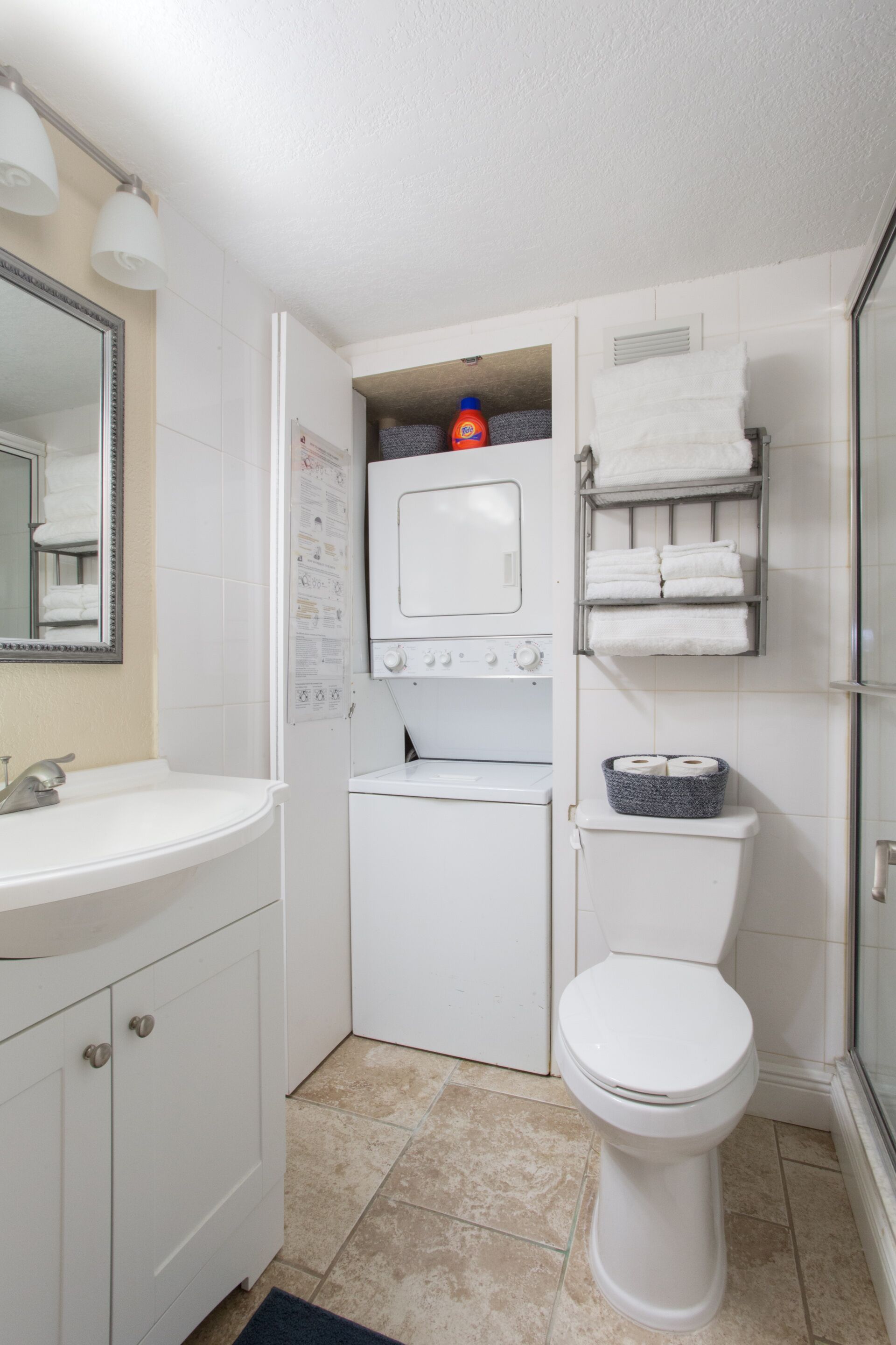Een kleine badkamer met een wastafel, een wasmachine, een toilet en een handdoekhouder.