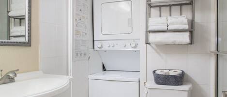 Een kleine badkamer met een wastafel, een wasmachine, een toilet en een handdoekhouder.