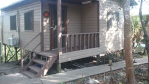 A small, single-story wooden cabin with a porch and a door.
