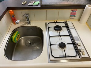 A kitchen with a stainless steel sink, a gas stove, and a bottle of orange dish soap. - Today's Relaxing and Fun Studio! Near Olympic Park! (Setagaya)
