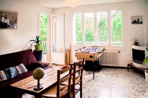 Une pièce chaleureuse avec une table en bois, des chaises, un canapé et une table de baby-foot.
