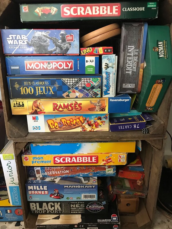 Une étagère contenant divers jeux de société, notamment Scrabble, Star Wars, Monopoly et d’autres.