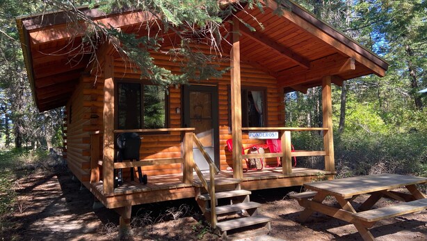 A wooden cabin with a porch, steps leading to the entrance, and a sign reading "Ponderosa". - Ponderosa Cabin Columbia Mountain Ranch (Columbia Falls)