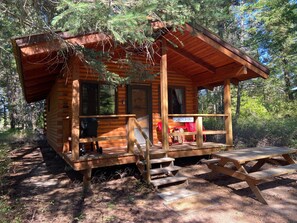 A wooden cabin with a porch, steps leading to the entrance, and a sign reading "Ponderosa". - Ponderosa Cabin Columbia Mountain Ranch (Columbia Falls)