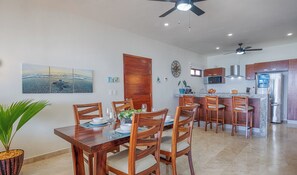 A modern kitchen with a central island, wooden chairs, and a dining table set for four.