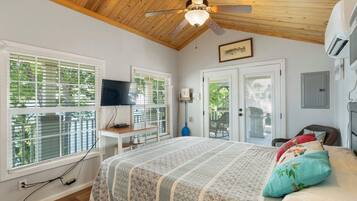 A bedroom with a bed, a ceiling fan, a TV, and a window with blinds.