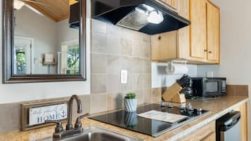 A modern kitchen with a stainless steel sink, a black stove, a microwave, and wooden cabinets.