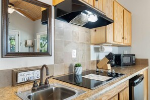 Uma cozinha moderna com pia de aço inoxidável, fogão preto, micro-ondas e armários de madeira.