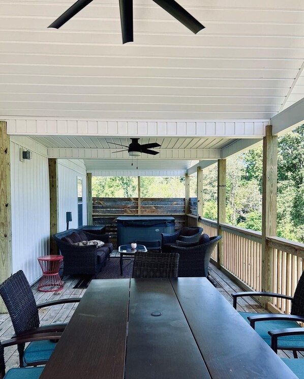 A covered outdoor patio with a dining table, chairs, and a grill area.