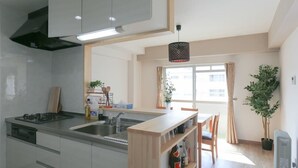 A modern kitchen with a central island, built-in appliances, and a dining area with a view of the city. - Tarbo's House TDS Recently Renovated (Nara)