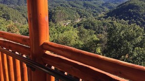 Un balcon en bois offrant une vue sur une chaîne de montagnes boisée.