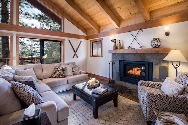 Great room has lofty beamed ceilings, gas fireplace, flat screen TV and deck