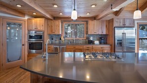 A modern kitchen with wooden cabinets, stainless steel appliances, and a central island. - Newly Remodeled Luxurious Craftsman Home  (IVGID)