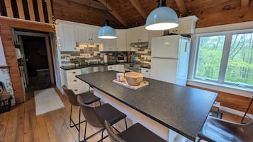 Una cocina moderna con una isla grande, armarios de madera e iluminación colgante.