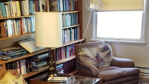 A cozy living room with a sofa, armchair, and a large bookshelf filled with books.