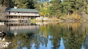 A lakeside cabin with a dock, surrounded by trees and a clear view of the lake.