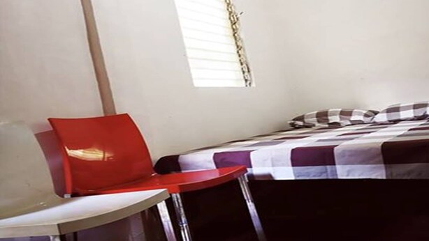 A small, simple room with a bed, a red chair, and a small table. - cheap room for short stay daily OR weekly in MACTAN CEBU PHILIPPINES (Lapu-Lapu City)