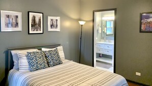 Un dormitorio con cama, ventilador de techo y baño con espejo y lavabo.
