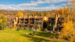 Una zona residencial con casas modernas, un césped bien cuidado y árboles de colores otoñales.