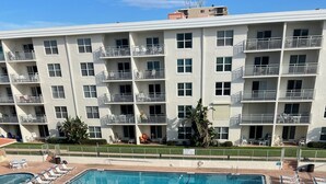 A large rectangular pool with multiple lanes, surrounded by lounge chairs and a multi-story building with balconies. - Seacoast Gardens lll Oceanfront Complex. NON DRIVING Beach. DIRECT OWNER BOOKING (New Smyrna Beach)