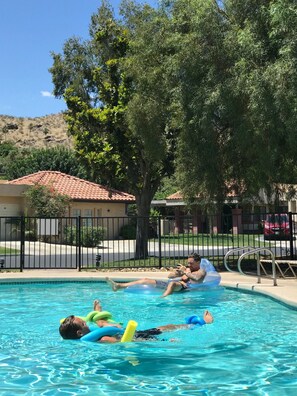 Una piscina con gente flotando en círculos inflables.