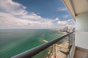 Een balkon met uitzicht op een strand en stadsachtergrond.