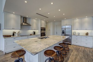 Enjoy cooking in this well-equipped kitchen with a large island, double oven, and stainless steel range hood.