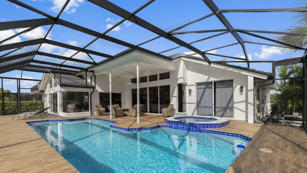 Una casa moderna con una gran piscina, terraza cubierta y techo de cristal.