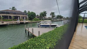 Enjoy the serene waterfront view from this building's interior, overlooking a tranquil body of water and a dock with a moored boat.