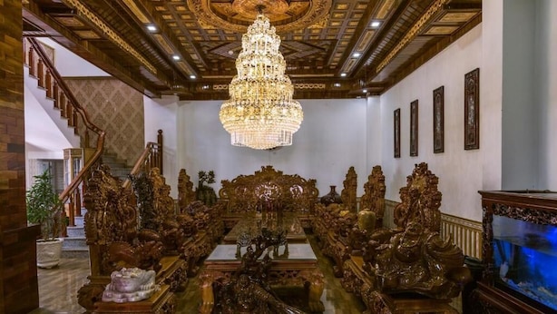 Una sala imponente con muebles de madera ornamentados, una gran lámpara de araña y una escalera.
