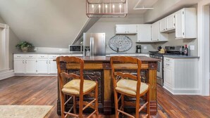 Una cocina con isla de madera, armarios blancos y una lámpara colgante.