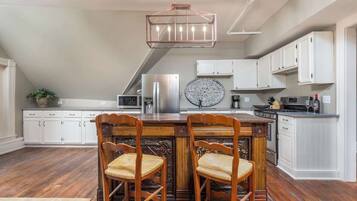 A kitchen with a wooden island, white cabinets, and a hanging light fixture.