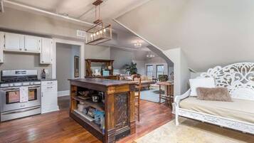 A spacious loft with a kitchen, dining area, and a large bed with ornate headboard.
