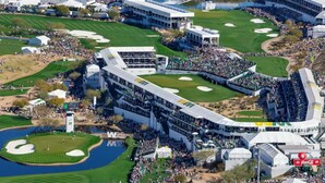 Un parcours de golf doté de tribunes pour les spectateurs, un grand bâtiment à plusieurs étages et un étang.