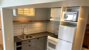Cocina compacta con un lavamanos integrado, estufa y refrigerador.