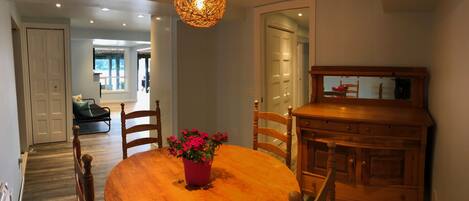 A dining area with a wooden table, chairs, a potted plant, and a wooden cabinet.