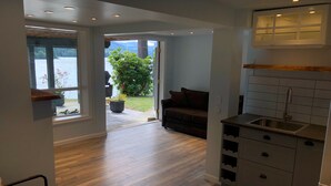 Cocina moderna con pileta integrada y muebles, piso de madera, y vista a un jardín y lago a través de amplios ventanales.