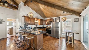 Een ruime keuken met houten vloeren, een centraal eiland met krukken en moderne apparatuur.