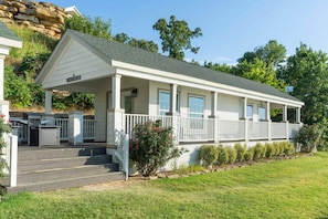 A white building with a covered porch, steps leading to the entrance, and a small outdoor kitchen area. - Castaway at CrossTimbers Marina (Sperry)