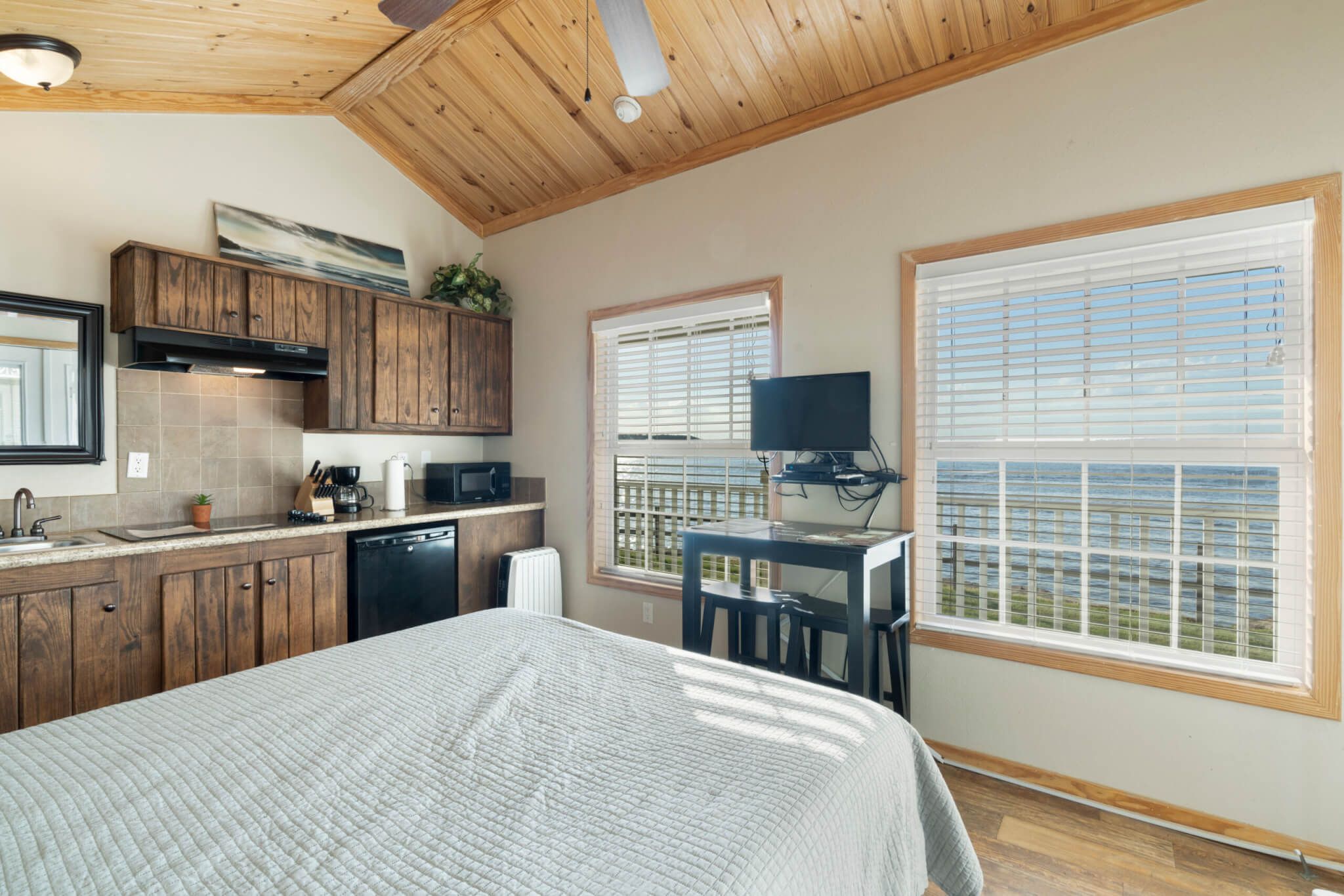 Une chambre avec un grand lit, un plafond en bois et une vue sur la mer par une fenêtre.