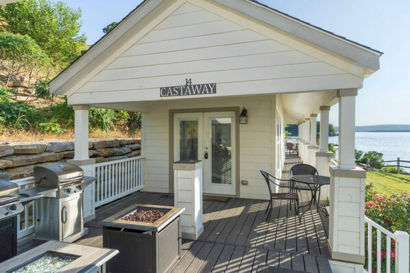 A covered outdoor area with a grill and barbecue, a seating area with tables and chairs, and a view of the water. - Castaway at CrossTimbers Marina (Sperry)