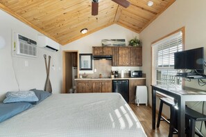 A compact room with a bed, wooden ceiling, kitchenette, and a TV. - Castaway at CrossTimbers Marina (Sperry)