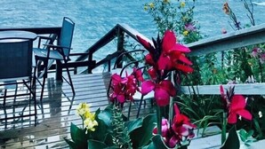 Una terrassa amb caires i una taula amb vista al mar, amb flors al primer pla.
