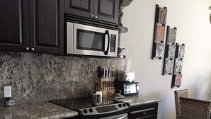 Uma cozinha moderna com armários escuros, eletrodomésticos de aço inoxidável e bancada de granito.