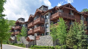 Un hotel a più piani con facciata in pietra e legno, balconi e cielo sereno.