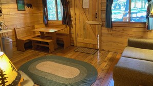 Interior acogedor de una cabaña con un banco de madera, una mesa y un tapete estampado.